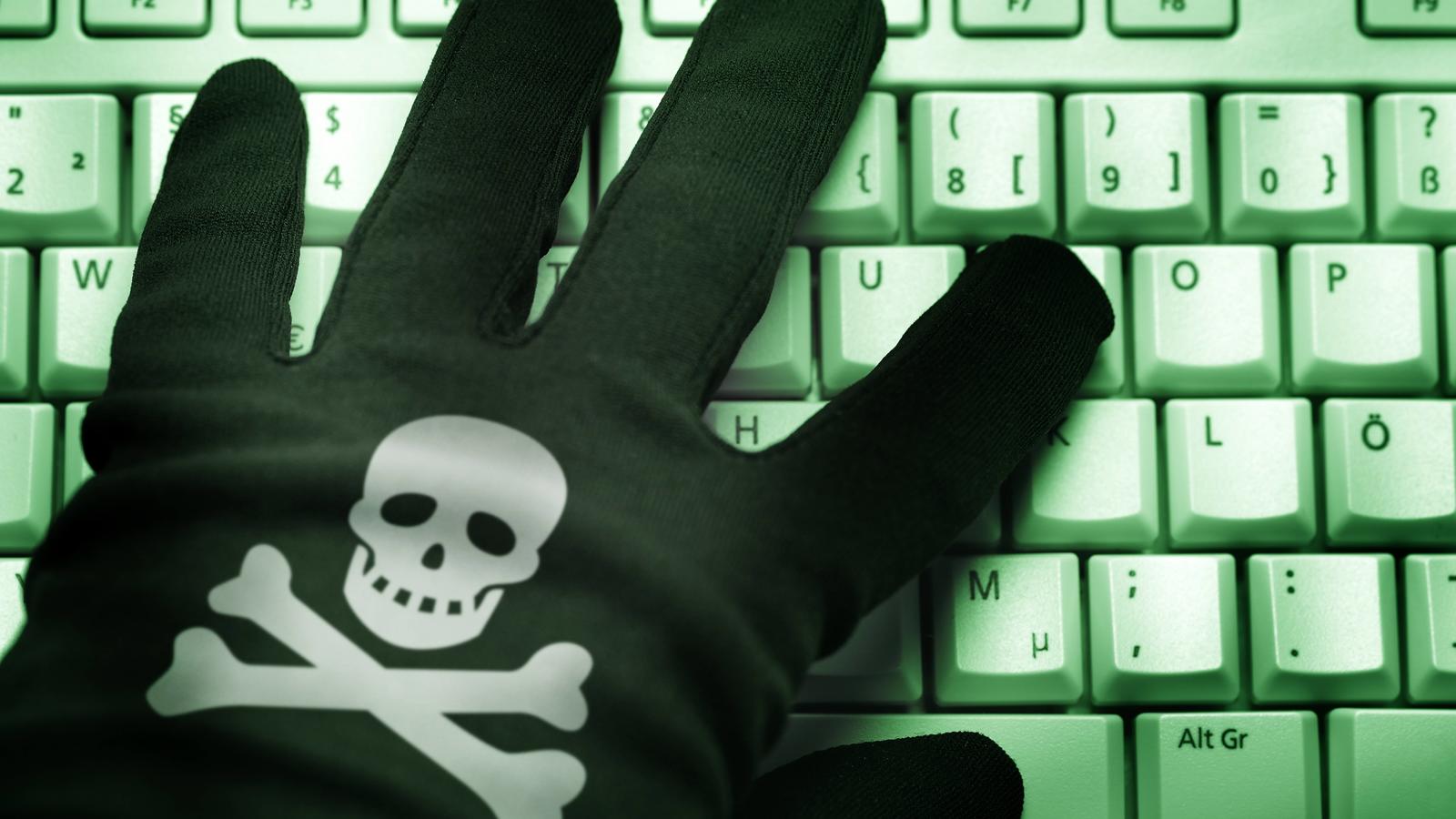 Schwarze Hand mit Totenkopf auf Computertastatur, CyberkriminalitätBlack Hand with Skull on Computer keyboard Cyber crime
