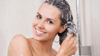 Young woman washing her head in the shower by shampoo