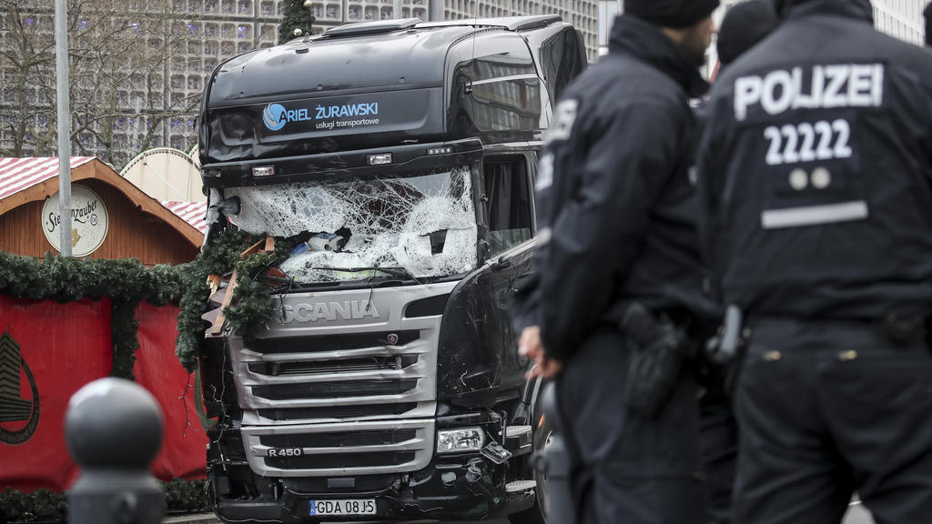 ARCHIV - Polizisten stehen vor dem zerstörten LKW am 20.12.2016 am Weihnachtsmarkt am Breitscheidplatz in Berlin. Nach der mutmaßlichen Manipulation von Akten im Fall des Attentäters Anis Amri sind in Berlin Wohnungen und Arbeitsplätze mehrerer Beamt