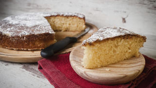 Portion of a sponge cake on a wooden plate in a studio shot.