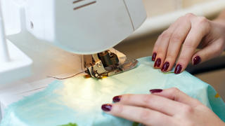 female hands working with silk on a sewing machine