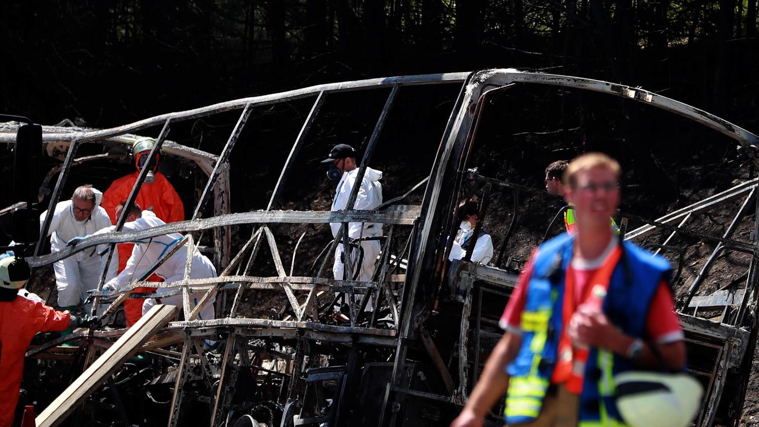 Ermittler und Helfer räumen am ausgebrannten Wrack des Unglücks-Busses auf.