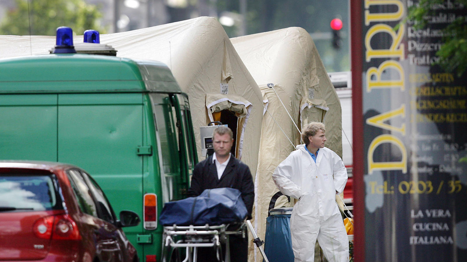 ARCHIV - Ein Bestatter schiebt am 15.08.2007 in Duiburg (Nordrhein-Westfalen) eine Trage mit einer verdeckten Leiche von einem Tatort. Zehn Jahre nach den Mafiamorden von Duisburg beschäftigen sich Politiker, Journalisten, Wissenschaftler und engagie