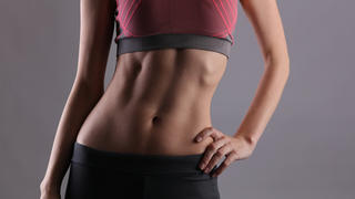 Sport, fit woman. Female with perfect abdomen muscles on grey background. Dieting, fitness, active lifestyle concept, copy space