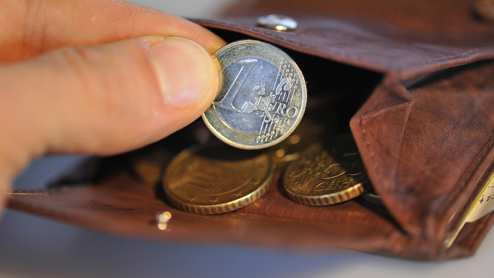 ARCHIV - ILLUSTRATION - Eine Hand nimmt am 22.01.2010 eine Euro-Münze aus einem Geldbörse, in dem sich weitere Münzen befinden. Mehrarbeit lohnt sich für Geringverdiener nicht immer. (zu dpa «Studie: Mehrarbeit rentiert sich für Geringverdiener nicht