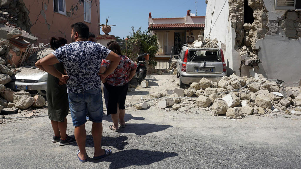 Personen betrachten am 22.08.2017 auf der Urlaubsinsel Ischia (Italien) teilweise zerstörte Gebäude. Mitten in der Ferienzeit hatte ein Erdbeben die Urlaubsinsel erschüttert. Foto: Cesare Abbate/ANSA/AP/dpa +++(c) dpa - Bildfunk+++