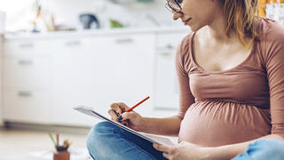 Pregnant woman at home relaxing by drawing with color pencils.