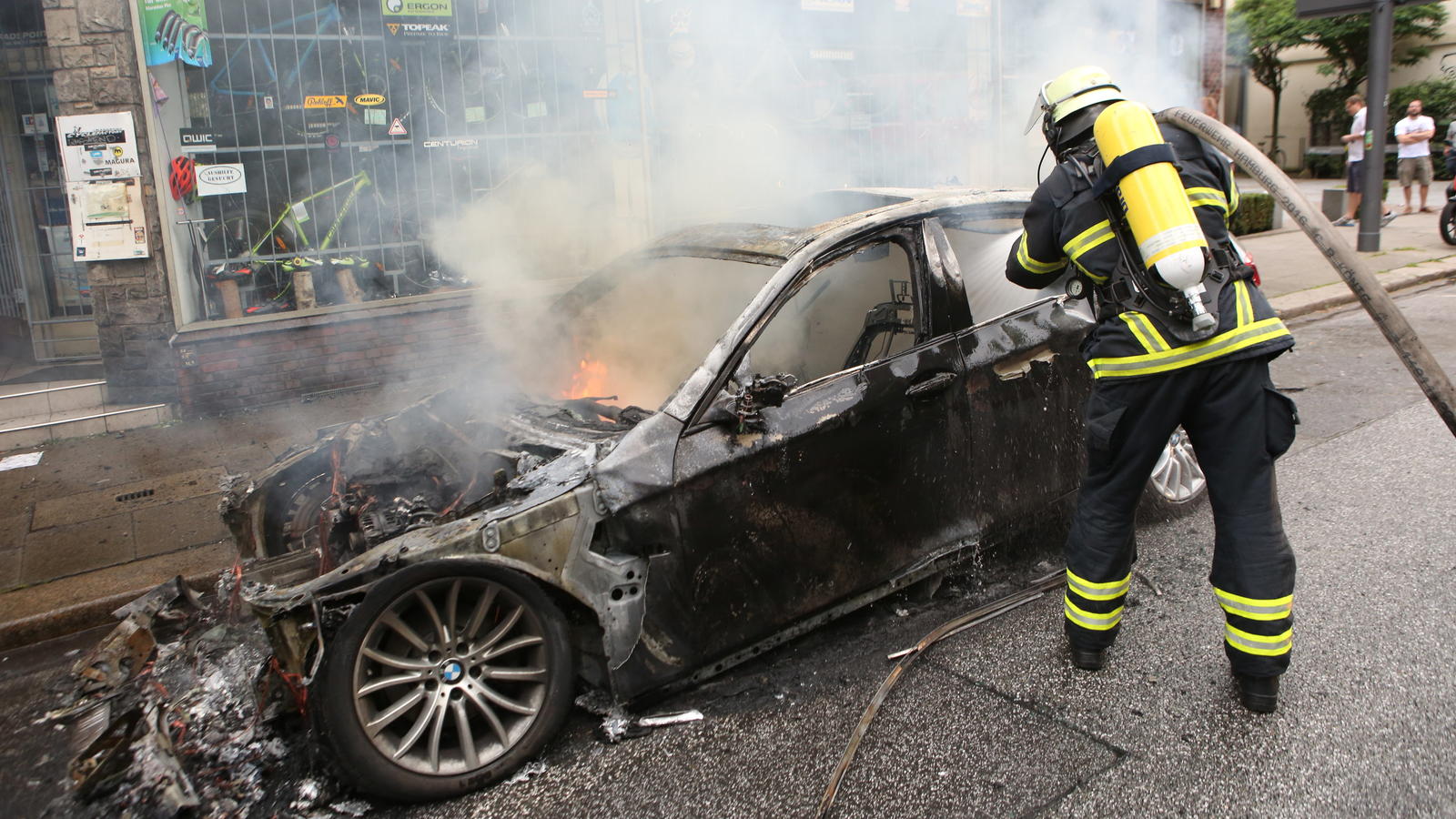 ARCHIV - Ein Feuerwehrmann löscht am 07.07.2017 in Hamburg in Altona ein brennendes Auto. Am 07. und 08. Juli kamen in der Hansestadt die Regierungschefs der führenden Industrienationen zum G20-Gipfel zusammen - im Umfeld des Treffens kam es zu gewal