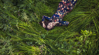 Beautiful young woman in dress lying in the grass in nature