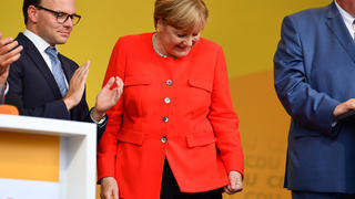 Bundeskanzlerin Angela Merkel schaut am 05.09.2017 in Heidelberg (Baden-Württemberg) auf dem Universitätsplatz bei einer Wahlkampfveranstaltung auf einen Fleck auf ihrer Jacke. Ein Tisch, der vor ihr stand, war von einem Gegenstand aus den Reihen des Publikums getroffen worden, dabei waren Spritzer auf Merkels Jackett gekommen. Links steht der Vorsitzende der CDU Heidelberg, Alexander Föhr. Foto: Uwe Anspach/dpa +++(c) dpa - Bildfunk+++