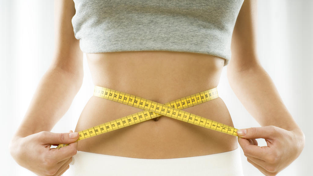 mid section view of a woman measuring her waist