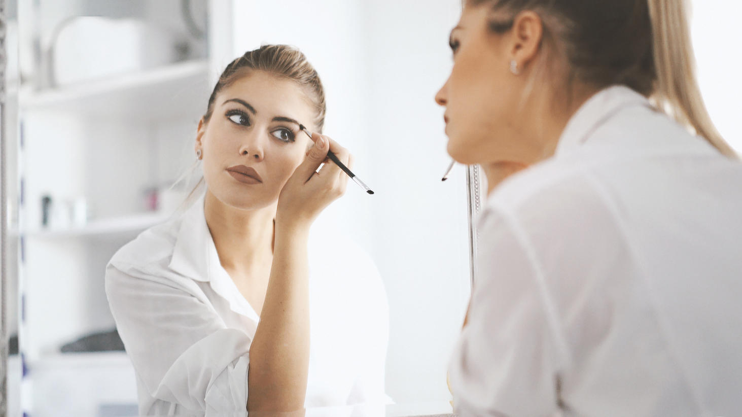 Eine Frau schminkt sich vor dem Spiegel.