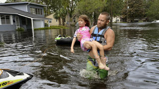 Tommy Nevitt trägt Miranda Abbott (6) am 11.09.2017 in Jacksonville (USA) durch das von Hurrikan Irma verursachte Hochwasser. Foto: Dede Smith/The Florida Times-Union/dpa +++(c) dpa - Bildfunk+++