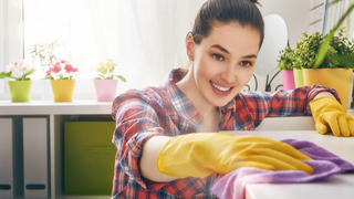 Beautiful young woman makes cleaning the house. Girl rubs dust.