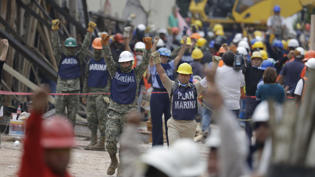 dpatopbilder - Rettungshelfer und Mitglieder der mexikanischen Marine heben am 21.09.2017 in Mexiko-Stadt (Mexiko) ihre Fäuste in die Luft - ein Zeichen, das auf der Suche nach Überlebenden des Erdbebens um Schweigen bittet. Nach dem schweren Erdbebe