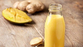 Detox drink. Smoothies with mango, ginger, turmeric in a glass bottle on old wooden background