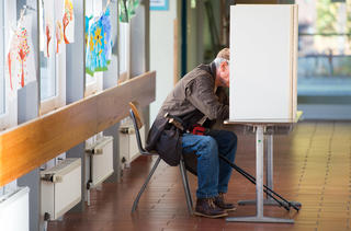 Ein älterer Mann sitzt am 15.10.2017 in Herzberg (Niedersachsen) an einer Wahlkabine bei der Stimmabgabe für die Landtagswahl in Niedersachsen. Foto: Swen Pförtner/dpa +++(c) dpa - Bildfunk+++