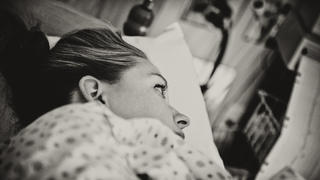 "Horizontal portrait of a young woman, laying in hospital bed in the labour and delivery ward, waiting to give birth to her child. Image is processed in a sepia tone and visible grain has been added. Image is processed from a 16 bit RAW file and profiled in ProPhoto RGB. All my images are professionally retouched.More from this series:"