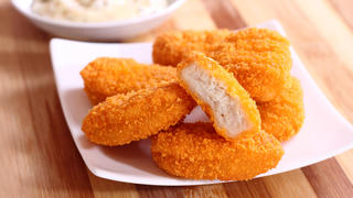 A pile of chicken nuggets on white plate with sauce