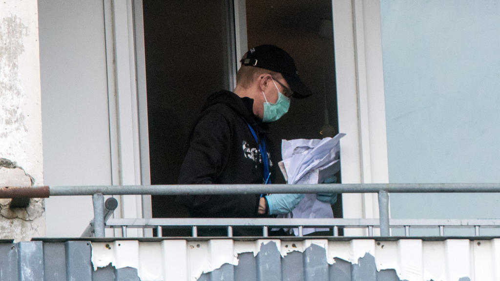 Ein Polizist sichert im Plattenbauviertel Neu Zippendorf in Schwerin auf dem Balkon der Wohnung eines Tatverdächtigen einen Stapel mit Papieren