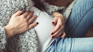 Young pregnant woman sitting on sofa close up