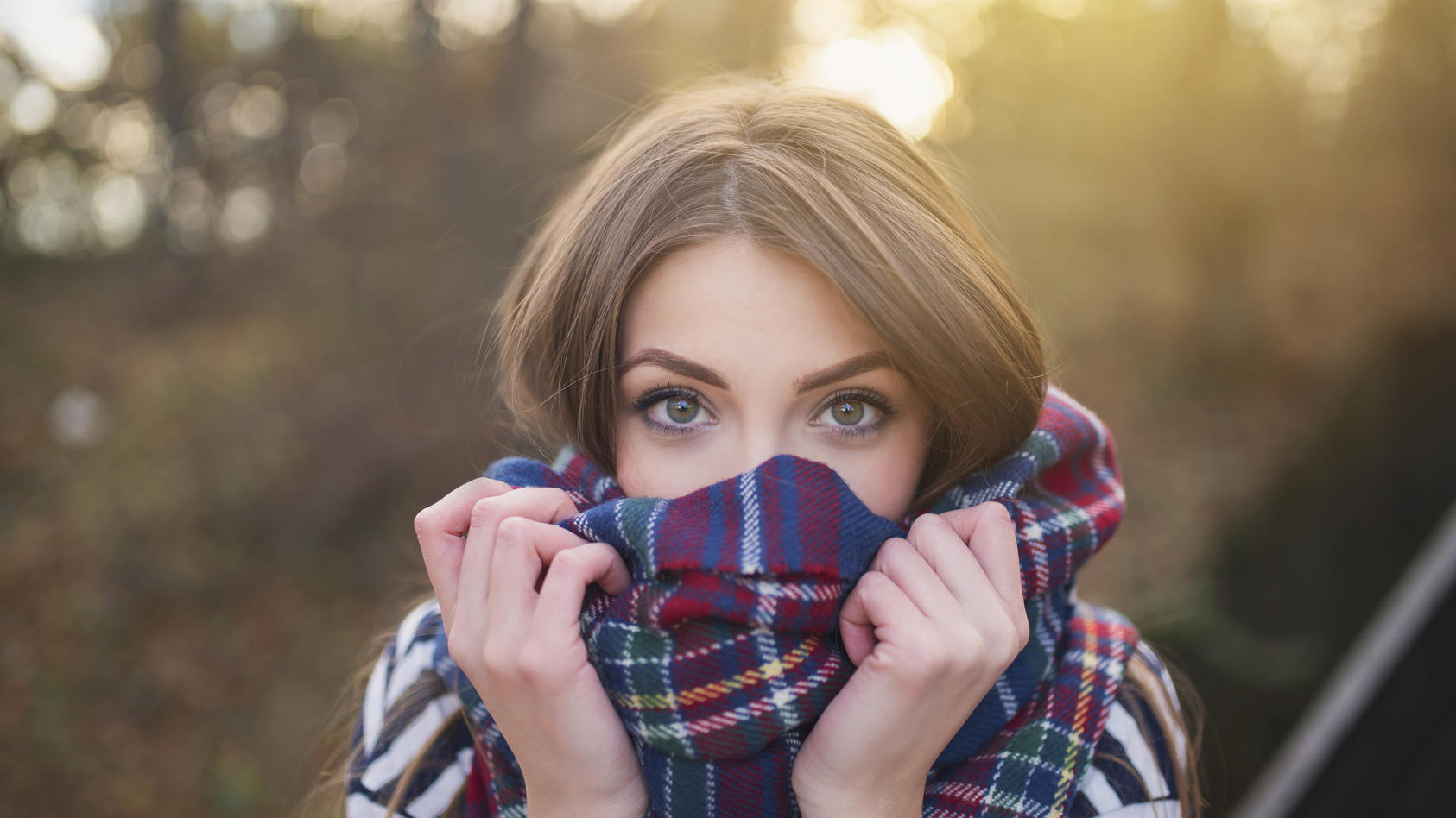 Portrait of a beautiful young woman with face wrapped with a plaid scarf.