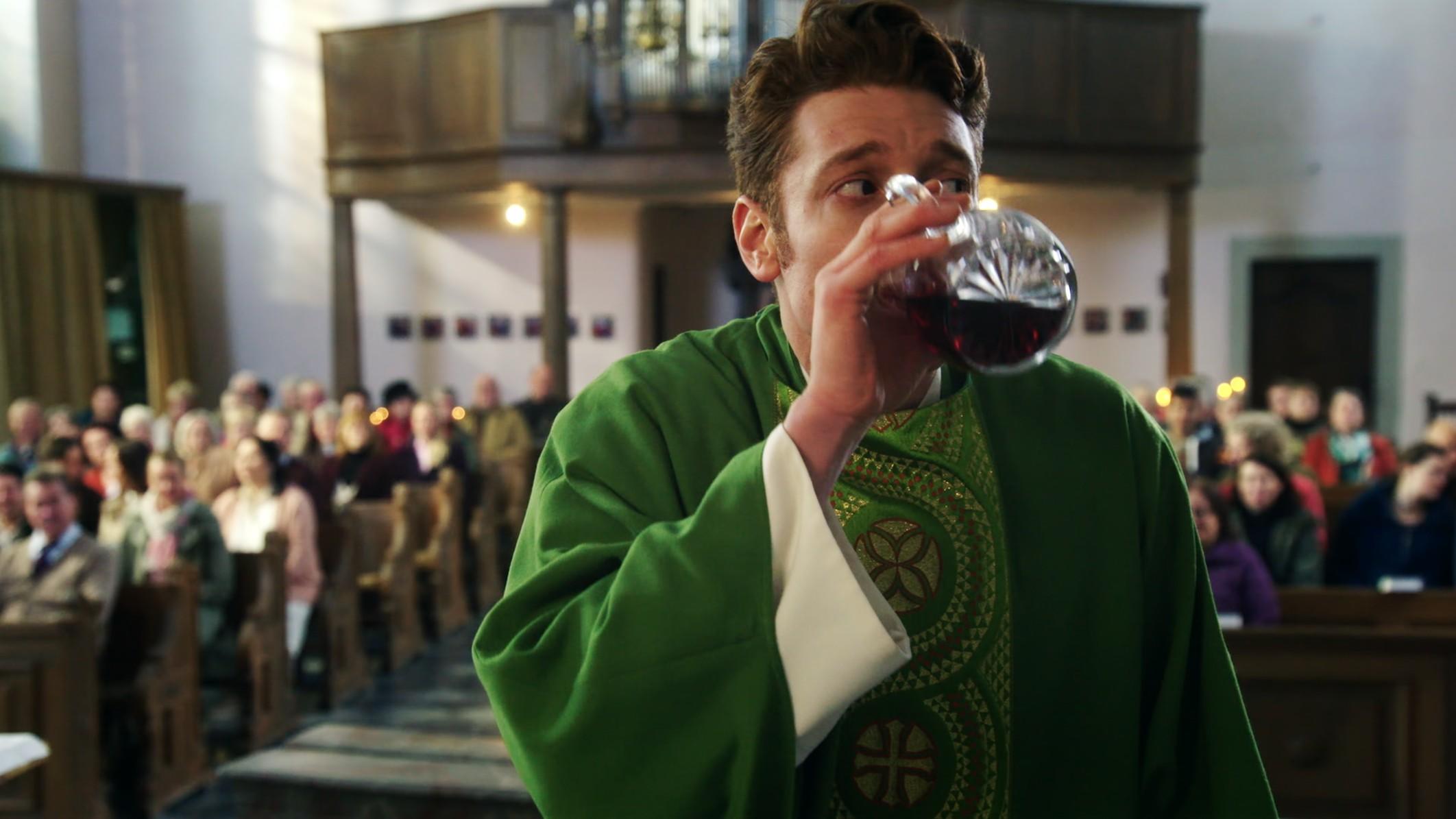 Maik trinkt im Gottesdienst in der RTL-Serie "Sankt Maik" den Messwein aus der Karaffe.