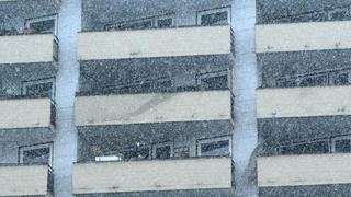 Eine Hochhausfassade mit Balkonen im Schnee