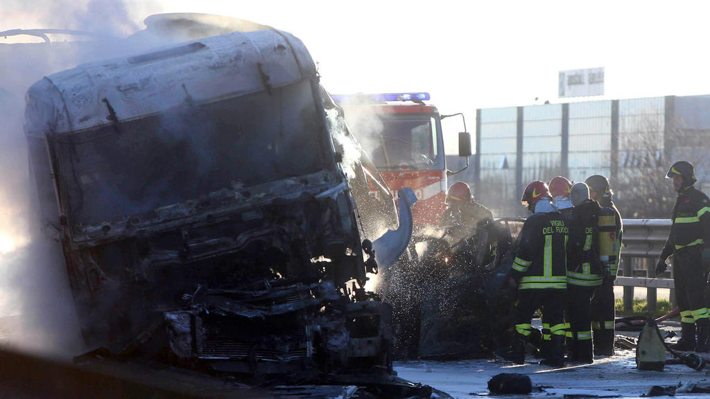 Feuerwehrleute begutachten am 02.01.2018 ein verkohltes Auto und einen LKW auf der Autobahn zwischen Brescia und Turin (Italien). Ein Tankwagen war in Brand geraten, nachdem er mit einem anderen Lastwagen zusammengeprallt war, sechs Menschen sind dab