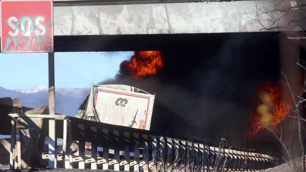 Die Rückseite eines LKWs ist am 02.01.2018 vor einem Feuer und einer schwarzen Rauchwolke auf der Autobahn zwischen Brescia und Turin (Italien) zu sehen. Ein Tankwagen war in Brand geraten, nachdem er mit einem anderen Lastwagen zusammengeprallt war,
