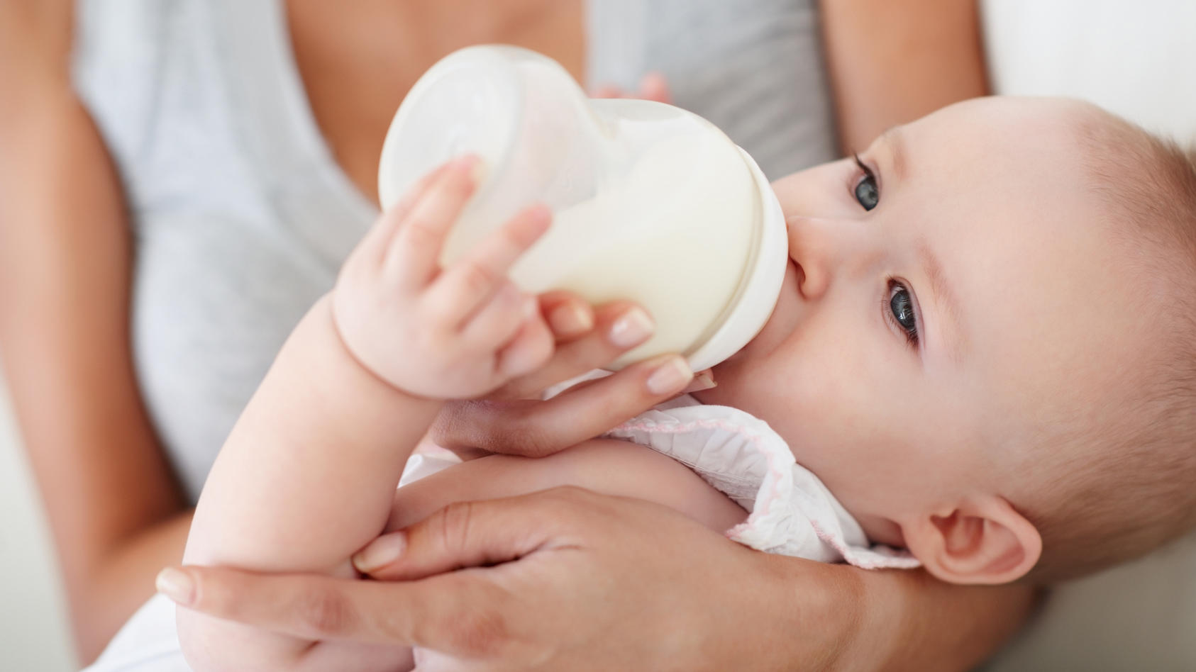 Mutter füttert Kind mit Babymilch