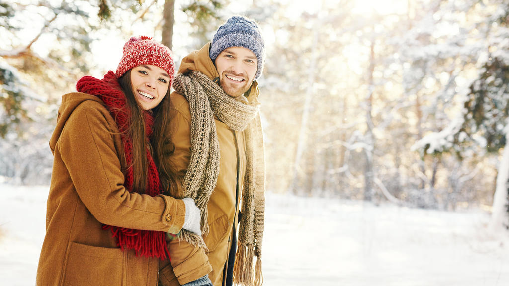Happy couple in winterwear taking walk in forest