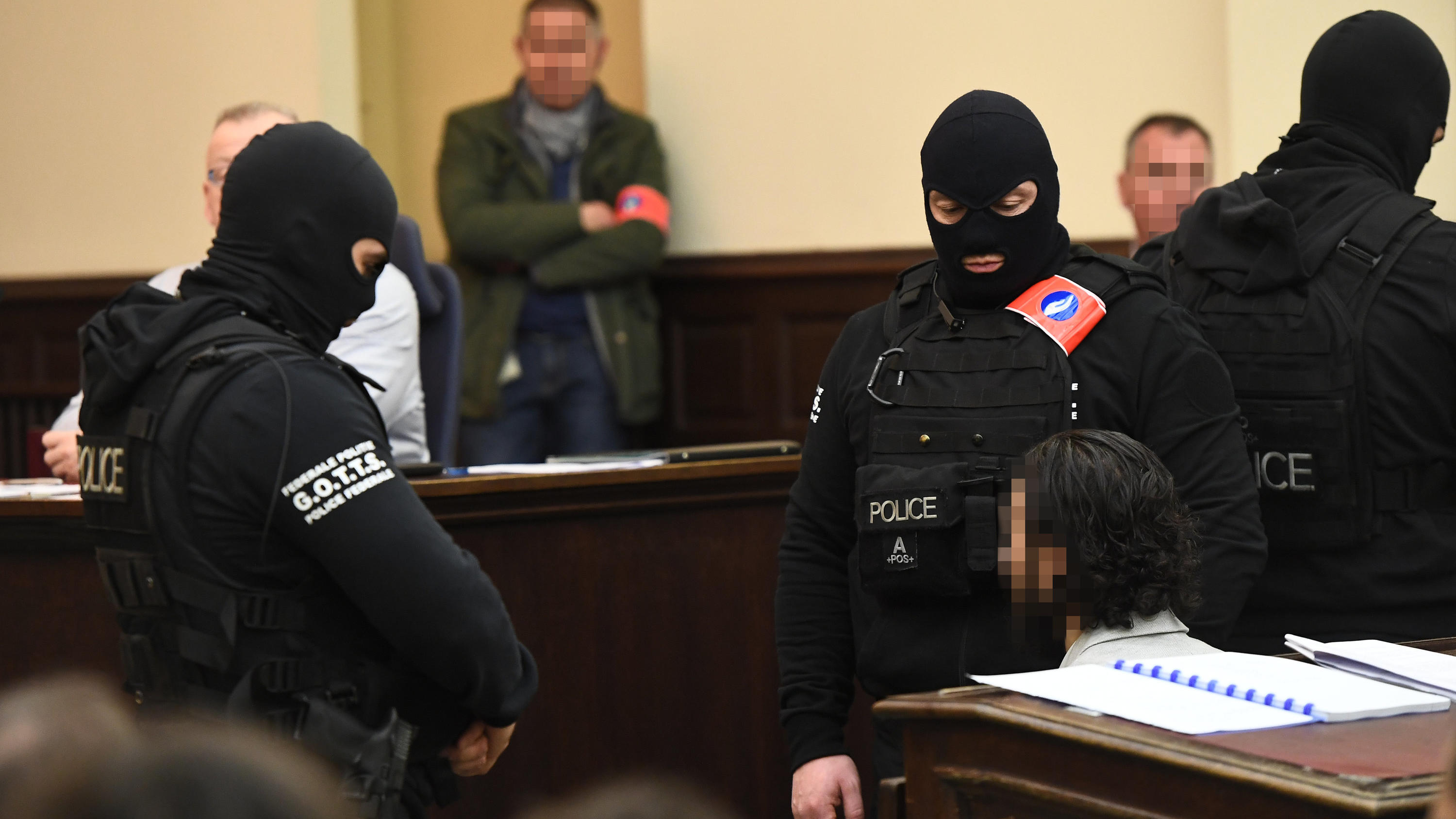 05.02.2018, Belgien, Brüssel: Polizisten bringen den mutmaßlichen islamistischen Terroristen Salah Abdeslam (r) in den Gerichtssaal. Der 28-jährige Franzose soll zur Terrorzelle gehören, die die schweren Anschläge in Paris im November 2015 und in Brü