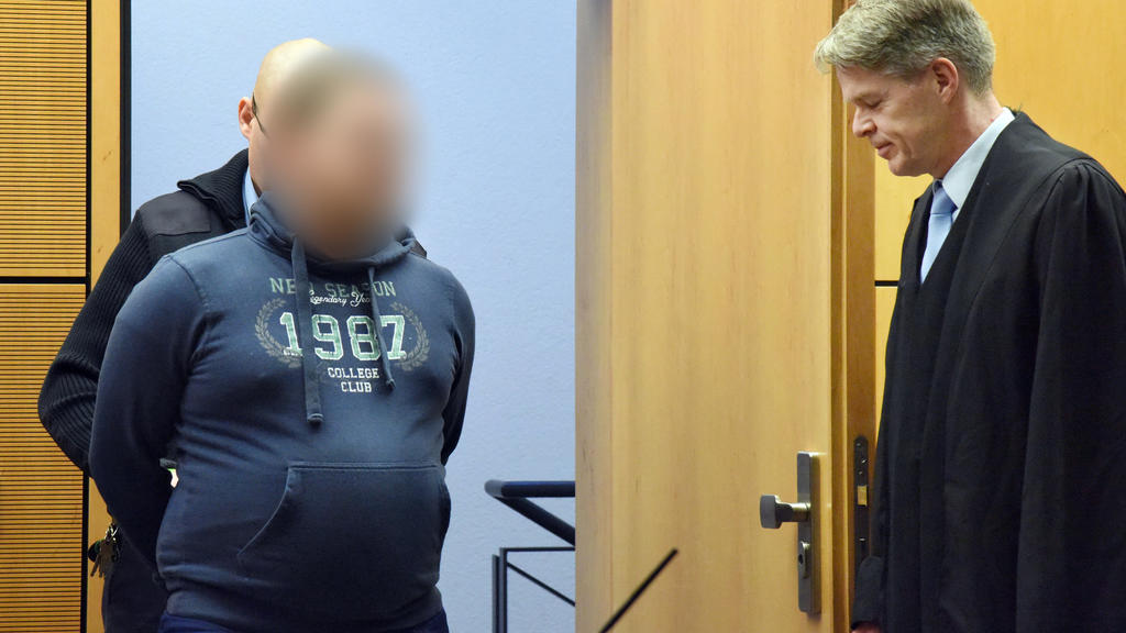 Hessen, Darmstadt: Einen wegen wegen Mordes aus Tötungswillen, Habgier und Heimtücke angeklagten 28-Jähriger (M) werden vor Prozessbeginn am Landgericht die Handschellen abgenommen, während sein Verteidiger Achim Flauaus (r) zusieht. Der