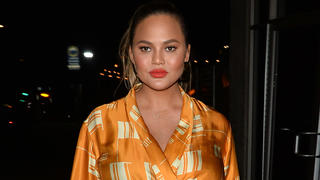 Chrissy Teigen Covers Her Baby Bump in a Mustard Colored Jacket