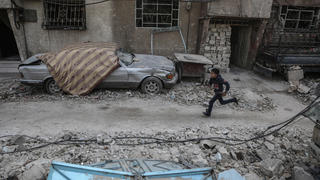 02.03.2018, Syrien, Douma: Ein syrischer Junge rennt durch die Überreste von durch Luftangriffen zerstörten Häusern. In Ost-Ghuta sind rund 400000 Menschen seit etwa fünf Jahren fast vollständig von der Außenwelt abgeschnitten. Foto: Samer Bouidani/dpa +++ dpa-Bildfunk +++