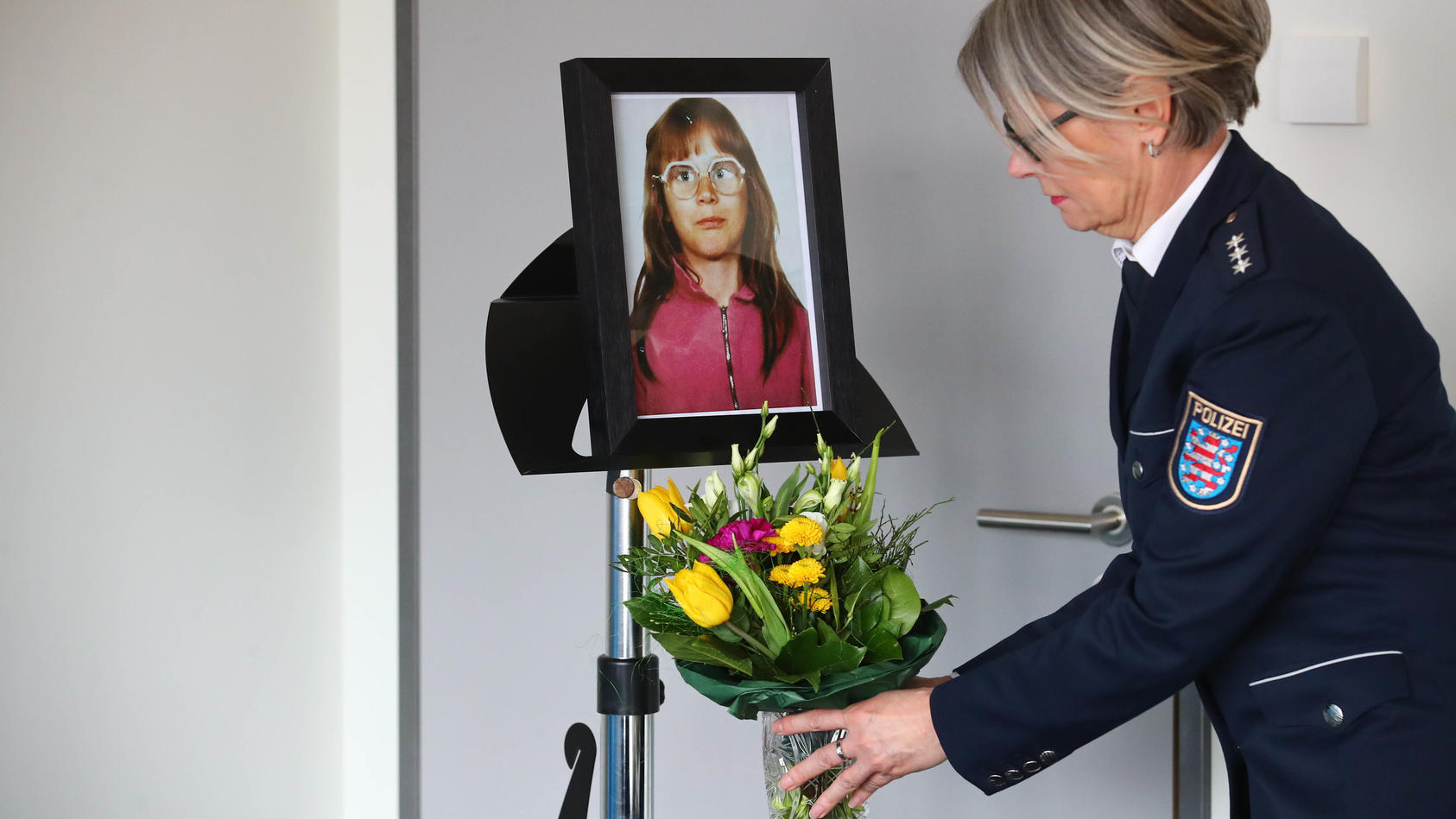 Thüringen, Jena: Eine Polizeibeamtin der Polizei Jena stellt einen Blumenstrauss unter das Foto der ermordeten Stephanie Drews