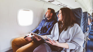 Ein Mann und eine Frau sitzen nebeneinander im Flugzeug.