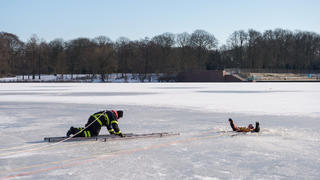 01.03.2018, Hamburg: Ein Feuerwehrmann kommt bei einer Übung im Stadtpark auf einem zugefrorenen See einem im Eis "eingebrochen" Mann zur Hilfe. Die Feuerwehr hat am Vormittag den Einsatz bei Eiseinbrüchen trainiert. Foto: Daniel Bockwoldt/dpa +++ dpa-Bildfunk +++