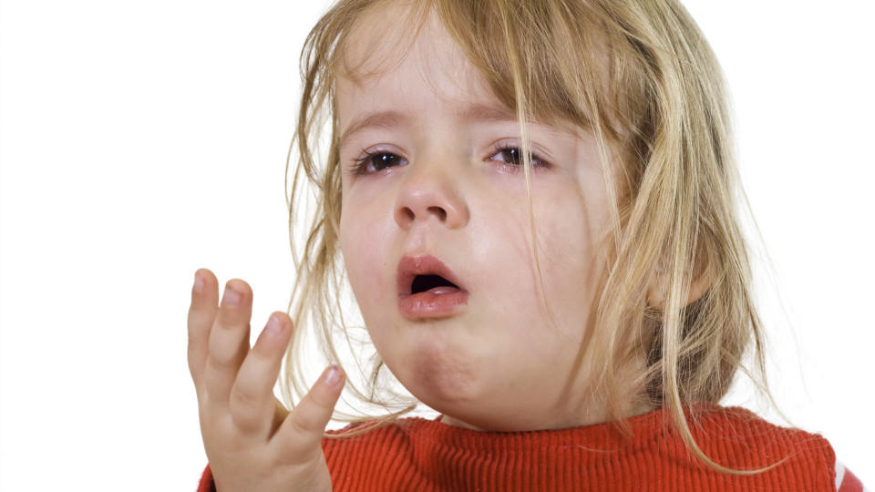 Ein kleines Mädchen ist erkältet und hustet in ihre Hand.