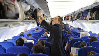 Ein Steward befüllt in einem Flugzeug der Fluglinie Air France ein Gepäckfach am Flughafen Charles de Gaulle in Paris (Foto vom 26.04.2012). Foto: Marc Müller dpa/lby | Verwendung weltweit