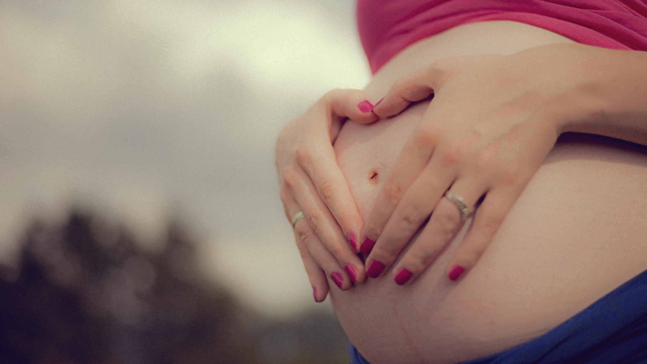 Schwangere Frau hält sich den Bauch,