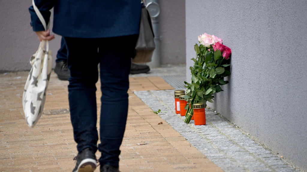 14.03.2018, Schleswig-Holstein, Flensburg: Blumen und Grablichter stehen an einem Mehrfamilienhaus. In dem Gebäude ist am Montag eine 17-Jährige nach Messerstichen gestorben. Bei dem Tatverdächtigen im Fall des gewaltsamen Todes einer 17-Jährigen in 
