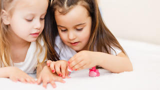 Two little girls painted their nails at home.