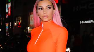 Kim Kardashian takes a night-time walk though Tokyo wearing a bright orange top. Poses for pictures with fans