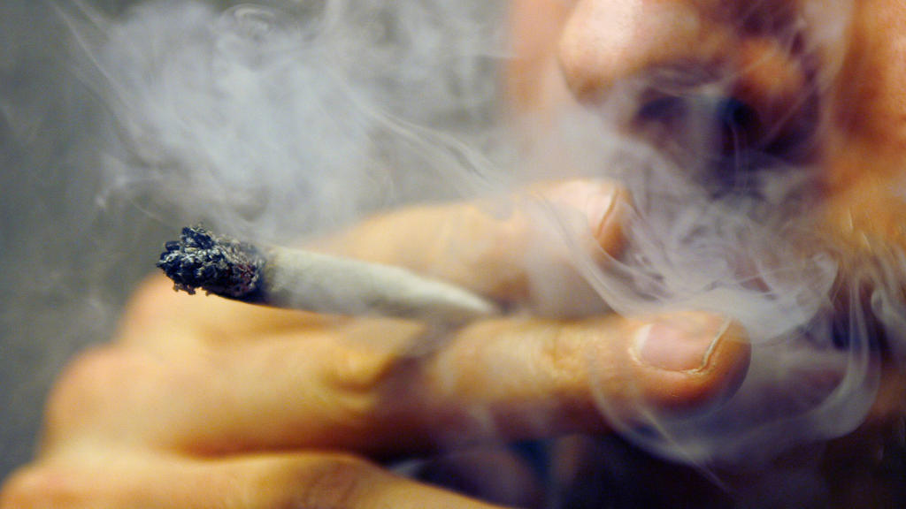 Ein Mann raucht einen Joint mit Marihuana.
