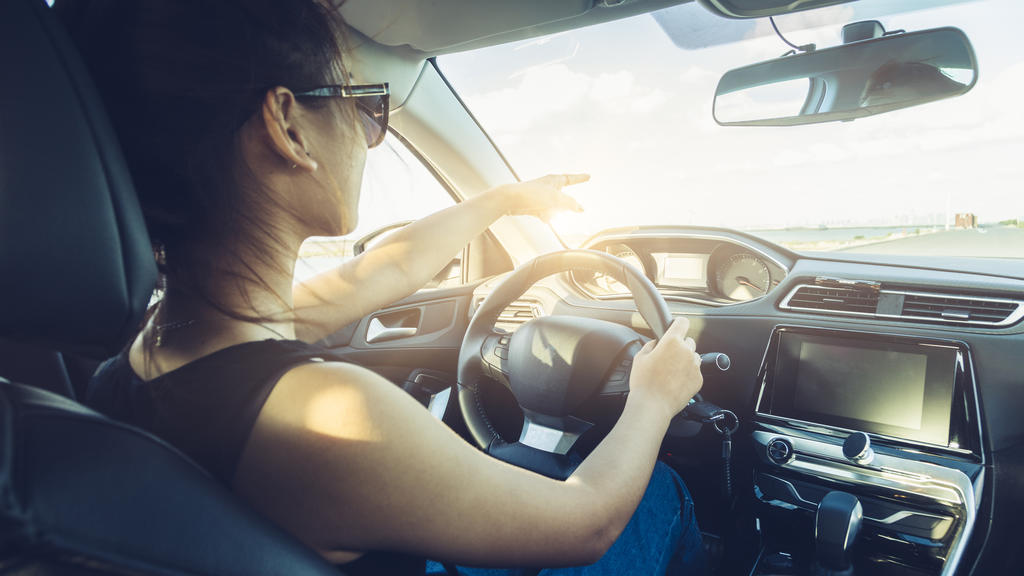 rear view of cool girl in sunglasses driving car.