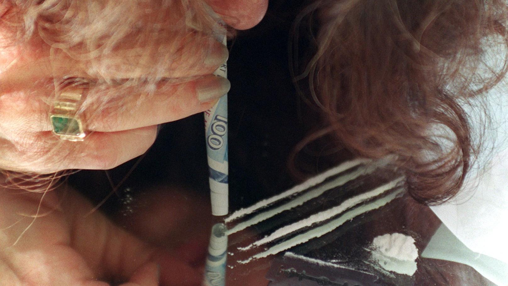 Eine junge Frau schnupft Kokain durch einen zusammengerollten Geldschein (gestellte Aufnahme von November 2000). Das Rauschgift, das lange Zeit als Modedroge der Reichen galt, findet immer größere Verbreitung: Dem Suchtbericht Deutschland zufolge hat
