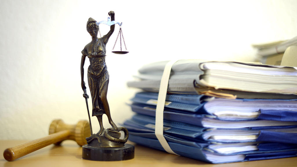 ARCHIV - ILLUSTRATION - Eine modellhafte Nachbildung der Justitia steht am 15.07.2014 im Raum eines Richters des Landgerichts Duisburg (Nordrhein-Westfalen) neben einem Holzhammer und einem Aktenstapel. Im Landgericht Bochum sollen Richter nun das Ur