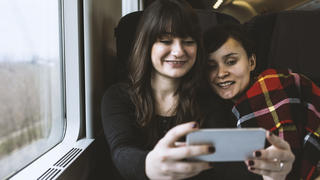 Two young woman taking a selfie on the train.